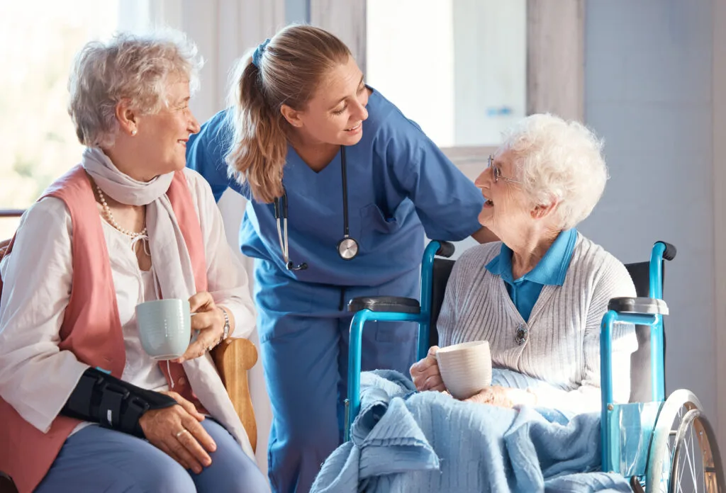 Nursing home, care and nurse with senior women doing healthcare checkup, examination or consultation. Medical, conversation and elderly woman in wheelchair consulting a doctor at retirement facility. elderly woman in wheelchair consulting a doctor at retirement facility